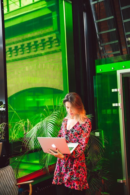 Person with glasses focused on work at a laptop in a bright workspace